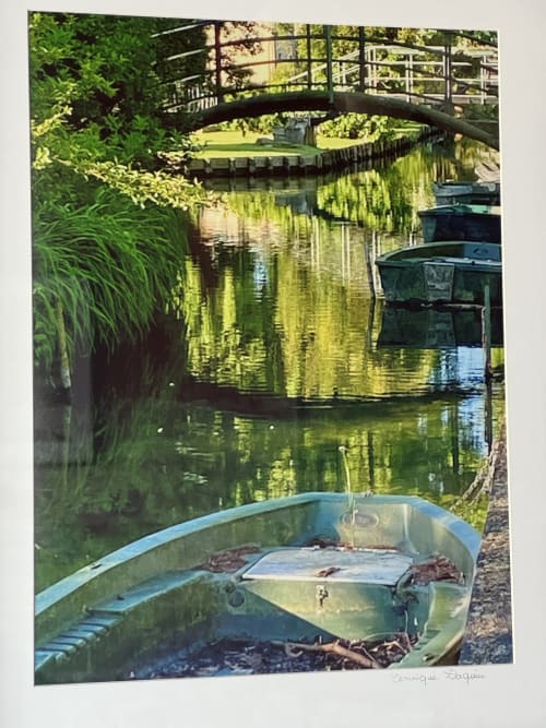 Peaceful canal scene at Au Bois Dormant B&B in Hesdin-la-Forêt with moored boats, arched bridge, and lush green vegetation