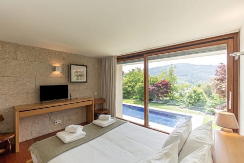 Quarto de luxo na Quinta Trindade com vista para piscina, Arouca Portugal - cama moderna, lareira, paisagem montanhosa