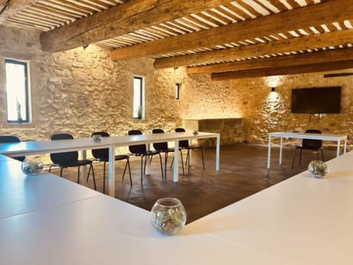 Salle de réception moderne au Jas de la Cascade avec murs en pierre apparente, poutres en bois, tables pour 50 convives