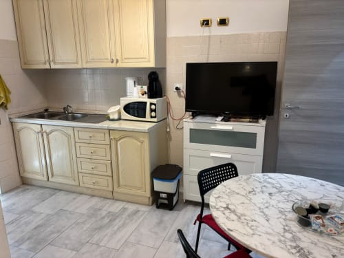 Zona cucina-soggiorno dell'appartamento ViOletta a Lido di Ostia con tavolo in marmo, elettrodomestici e televisore