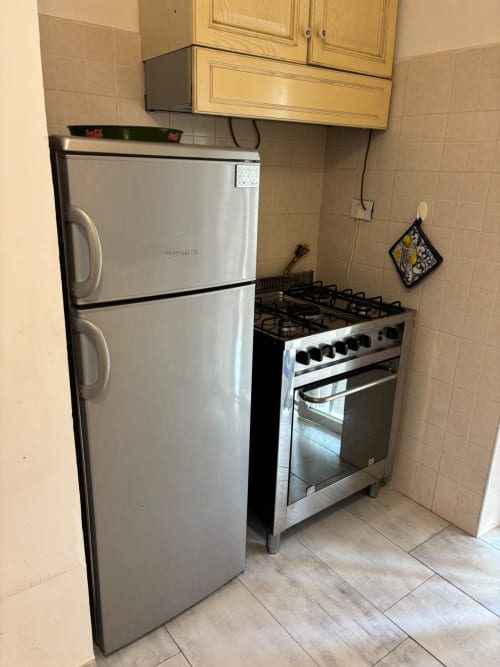 Cucina compatta con frigorifero bianco, fornello a gas e mobili in legno nell'appartamento ViOletta a Lido di Ostia