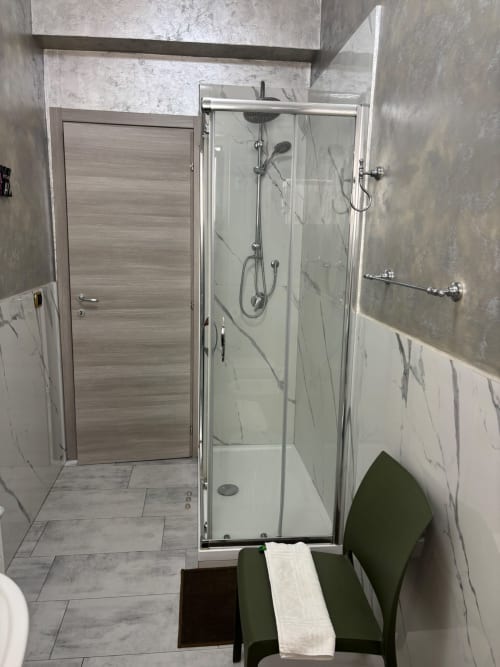Bagno moderno con cabina doccia in vetro, rivestimenti in marmo e rubinetteria cromata nell'appartamento ViOletta a Lido di Ostia