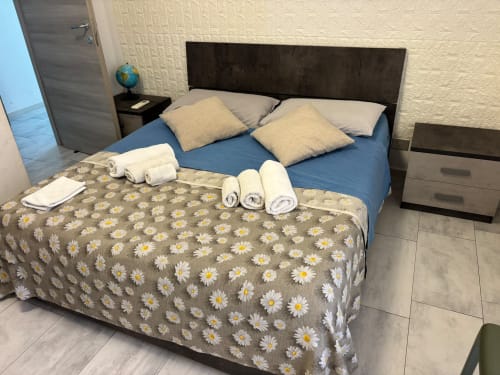 Camera da letto dell'appartamento ViOletta a Lido di Ostia con letto matrimoniale, copriletto margherita, cuscini, asciugamani arrotolati e design moderno