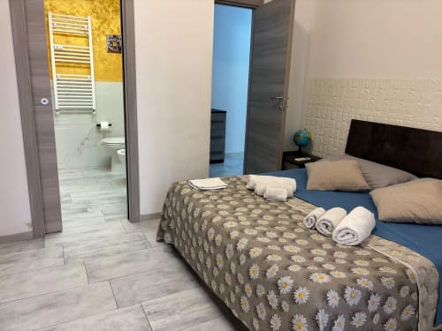 Camera da letto dell'appartamento ViOletta a Lido di Ostia con coperta a margherite, bagno privato e comfort moderni