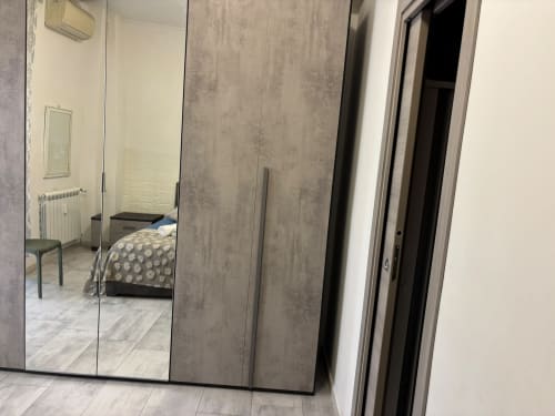 Camera moderna a ViOletta Ostia con armadio specchiato, letto con biancheria decorata e pavimenti piastrellati
