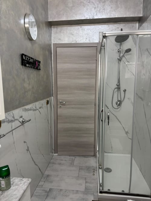 Bagno moderno con doccia in marmo e pavimentazione a lisca di pesce presso l'appartamento ViOletta a Lido di Ostia