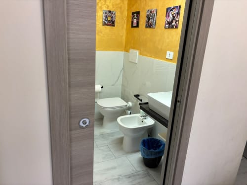 Bagno moderno nell'appartamento ViOletta a Lido di Ostia con bidet, WC, lavabo e parete accent gialla