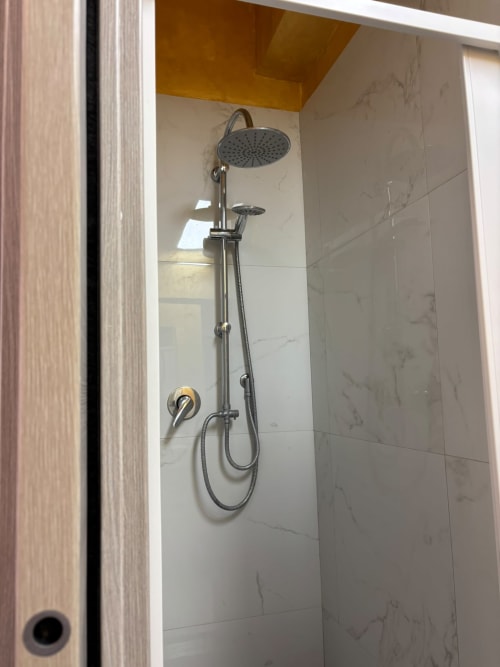 Moderno soffione pioggia e doccetta manuale in bagno rivestito di marmo all'appartamento ViOletta, Lido di Ostia