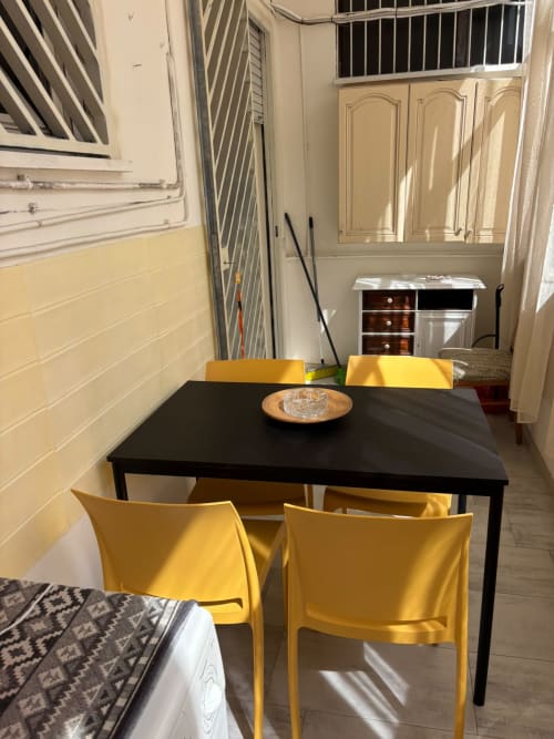 Zona pranzo moderna con tavolo nero e sedie gialle nell'appartamento ViOletta a Lido di Ostia, Italia