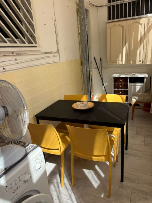 Zona living moderna con tavolo nero e sedie gialle nell'appartamento ViOletta al Lido di Ostia, con elettrodomestici in cucina
