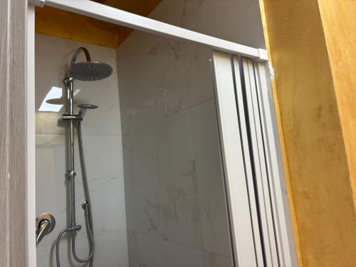 Elegante cabina doccia con soffione a cascata nell'appartamento ViOletta a Lido di Ostia