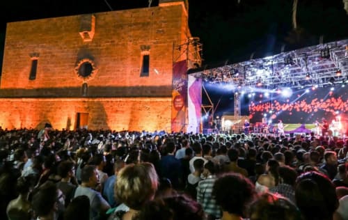 Concerto all'aperto nella fortezza storica di Carini con grande folla e palco illuminato di notte