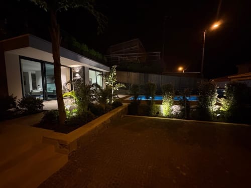 Villa de Luxo BHF Residences com piscina iluminada, pátio e edifício branco moderno à noite em Arco da Calheta
