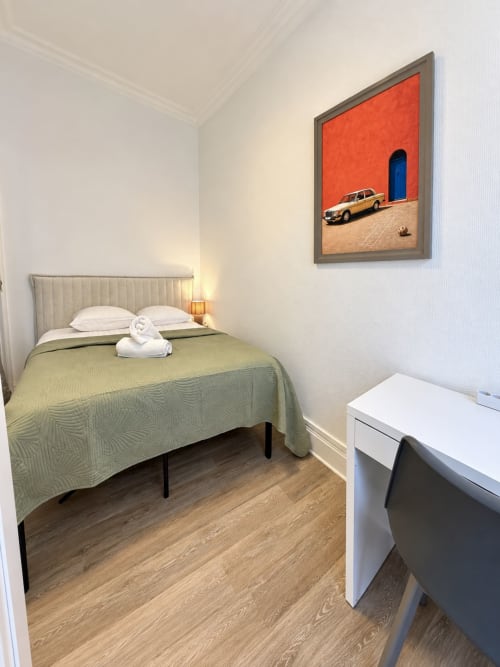 Chambre moderne de l'hôtel Nancy-Place avec literie verte, oreillers blancs, plancher en bois et art mural coloré