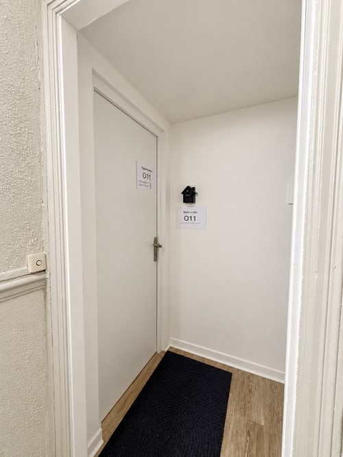 Entrée de la chambre O11 à l'hôtel Nancy-Place, porte blanche avec poignée en laiton et signalétique dans un couloir impeccable