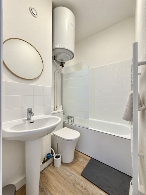 Salle de bain moderne de la chambre O11 de l'hôtel Nancy-Place avec lavabo, toilettes, douche et chauffe-eau mural