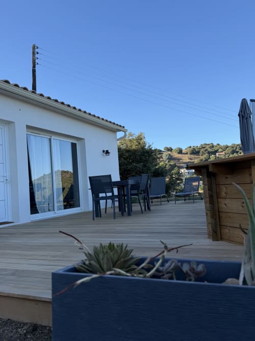Terrasse moderne du Petit Coin de Paradis B&B à Alata avec sièges, vue sur mer et paysage de collines