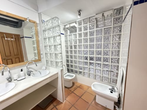 Baño moderno en apartamento Stay Gest Valencia con doble lavabo, mampara de ducha de bloques de vidrio y baldosas de terracota