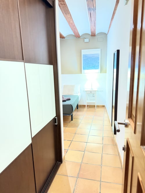 Pasillo del apartamento urbano Bisbe Colón, València, con baldosas de terracota que conducen al dormitorio con vistas al mar