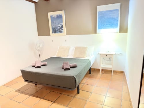 Dormitorio luminoso con cama queen, toallas rosas, mesita de noche blanca y dos acuarelas azules en el apartamento Stay Gest