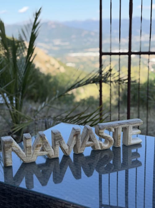Panneau en bois « NAMASTE » avec vue sur la vallée montagnarde depuis la terrasse du Petit Coin de Paradis B&B à Alata, France