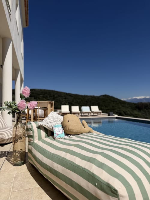 Chaise longue de luxe avec coussin à rayures vertes, fleurs roses et vue sur les montagnes au Petit Coin de Paradis à Alata