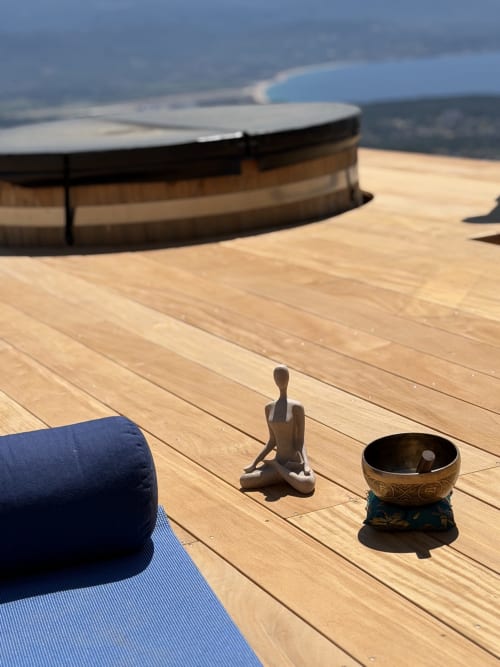 Tapis de yoga et bol chantant sur une terrasse en bois avec vue sur la mer au Petit Coin de Paradis, Alata