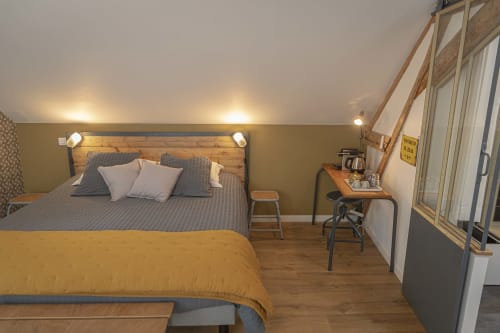 Chambre cosy de la maison d'hôtes Les Olivanies à Monthelon avec lit en bois, couette jaune et équipements modernes