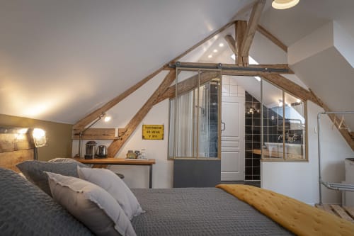Chambre spacieuse avec poutres apparentes, salle de bain moderne attenante et plafond cathédrale au gîte Les Olivanies, Monthelon.