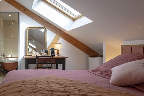 Chambre mansardée moderne aux Olivanies avec poutres inclinées, lucarne, coiffeuse et literie violette