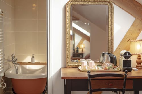 Salle de bain du cottage aux Olivanies : baignoire rouge, miroir doré, bureau en bois, cafetière et bouilloire.