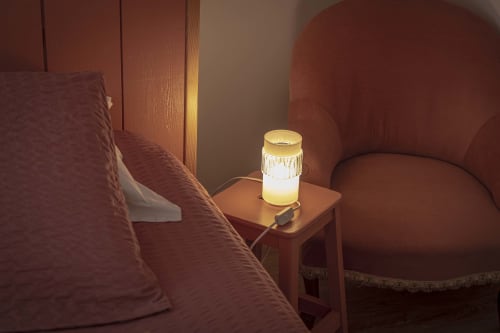 Coin chambre cosy au gîte Les Olivanies avec lampe de chevet lumineuse et mobilier en tissu bordeaux à Monthelon