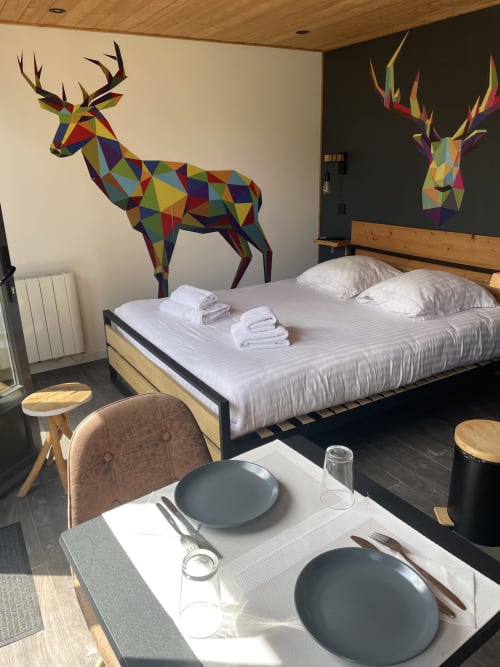 Chambre moderne du gîte Gîtes D'Armor avec art géométrique coloré de cerf, coin repas et literie blanche