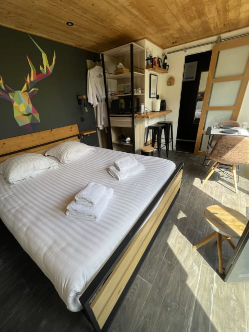 Chambre moderne aux Gîtes d'Armor avec lit queen-size, plafond en bois, art mural coloré et équipements à Tréguídel