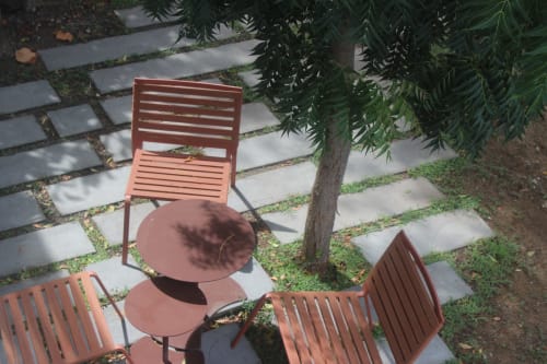 Terrasse avec coin détente à la Villa Mahogany, chaises en bois autour d'une table ronde sur dallage en pierre, entourée de végétation tropicale