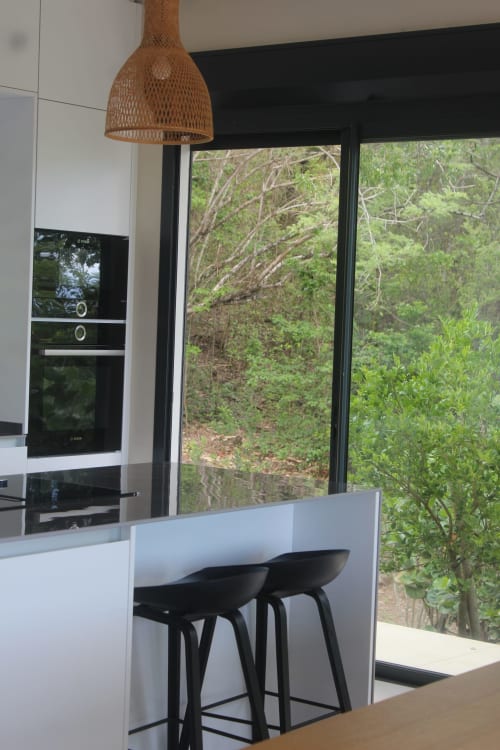 Cuisine moderne avec suspension tressée, coin bar et grandes baies vitrées sur le jardin tropical à Villa Mahogany