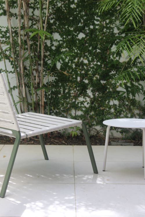 Espace de détente extérieur donnant à la suite parentale à la villa Mahogany avec chaise verte, table blanche et jardin tropical luxuriant en Martinique
