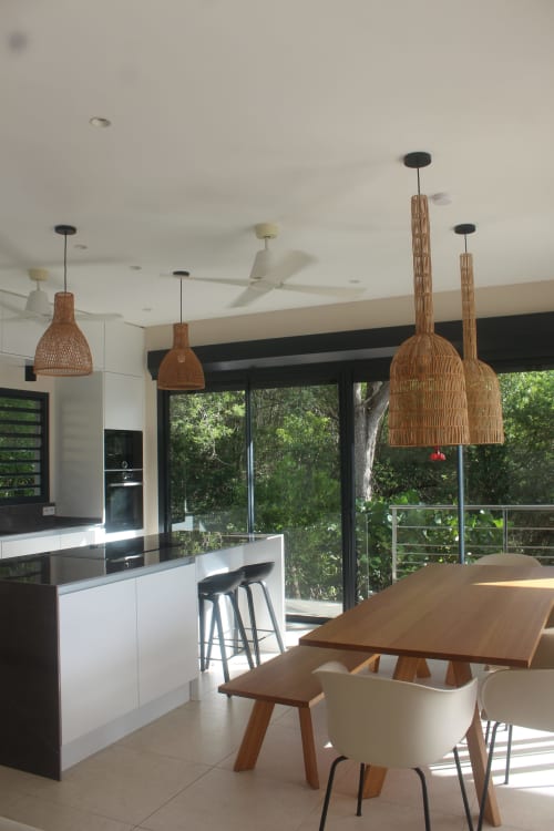 Cuisine et salle à manger moderne à Villa Mahogany avec suspensions en tissé, table en bois et vue sur mer aux Anses d'Arlet