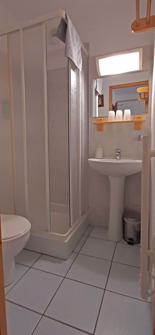 Salle de bain privée en chambre triple au Chalet De La Yodine avec douche, lavabo sur piédestal, toilettes et étagère en bois