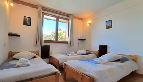 Chambre triple avec salle de bains partagée au Chalet De La Yodine, dotée de trois lits en bois et vue sur les montagnes