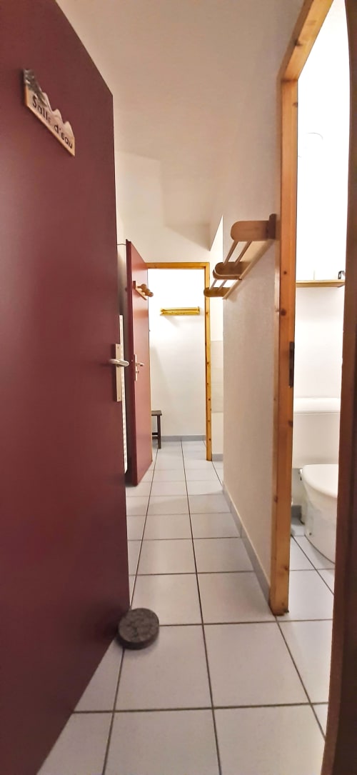 Couloir avec portes bordeaux au Chalet De La Yodine, montrant les salles de bains communes et les boiseries
