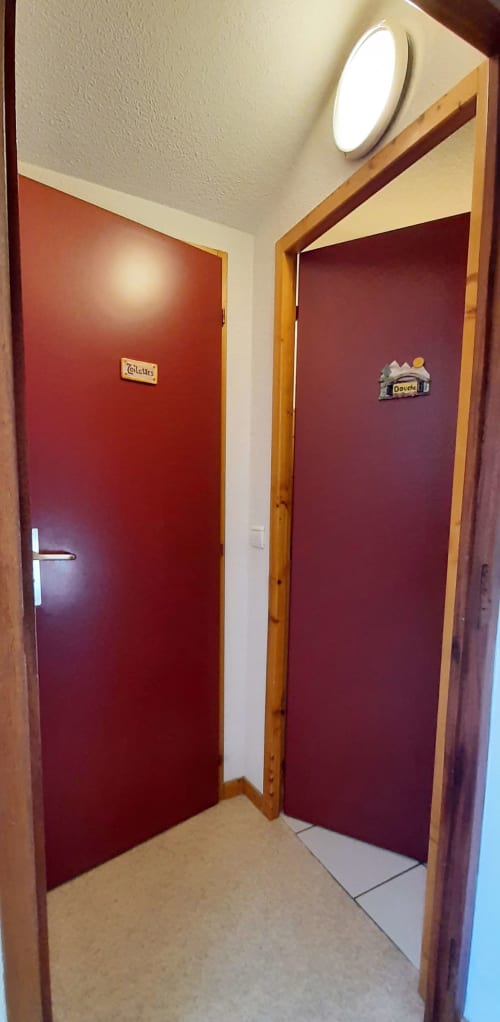 Couloir avec deux portes bordeaux marquées Toilets et Douche au Chalet De La Yodine à Feissons sur Salins, France