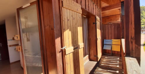 Couloir intérieur du chalet en bois avec portes ouvertes et balcon ensoleillé au Chalet De La Yodine en Haute-Savoie