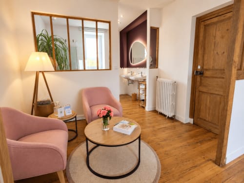 Suite chambre élégante aux Chambres D'Hespéris à Pleyben avec fauteuils roses, miroir en bois et salle de bain privée