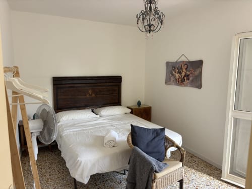 Camera da letto dell'appartamento Lovelyloft a Modica con letto in legno, biancheria bianca e vista sulla città