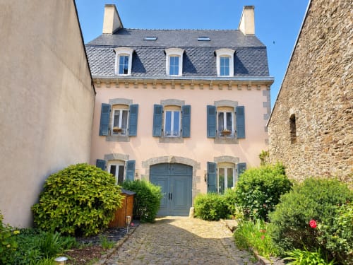 Charmant gîte en pierre rose Les Chambres D'Hespéris à Pleyben, France avec volets bleus et jardin de cour