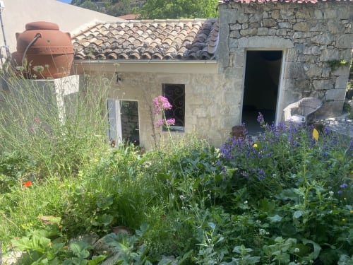 Giardino di villa mediterranea a Modica con muri in pietra, piante fiorite, tetto in cotto e fascino rustico presso Lovelyloft
