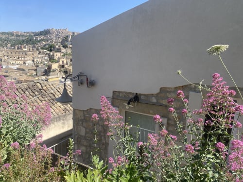 Terrazza panoramica della villa Lovelyloft a Modica con fiori rosa che si affacciano sull'architettura storica della città