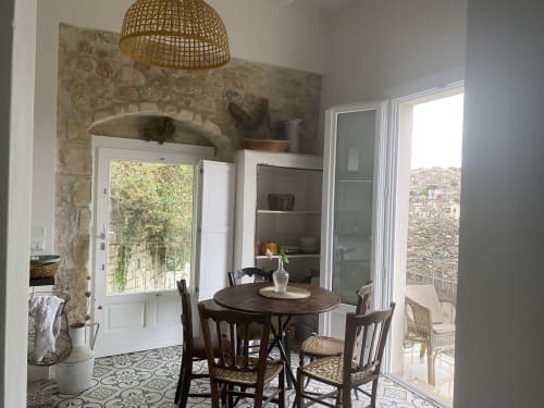Zona pranzo della villa Lovelyloft a Modica con tavolo rotondo, lampada sospesa intrecciata e vista della città attraverso le porte in vetro