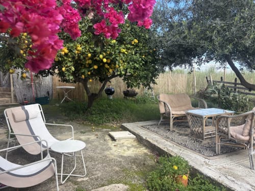 Patio esterno con lettini sotto la vibrante buganvillea della villa Lovelyloft a Scicli, Sicilia